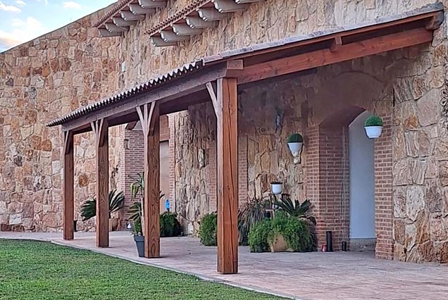 Pergola rústica para casa cueva con fachada de piedra