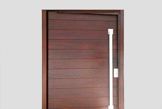 Puerta pivotante de madera sobre eje excéntrico. Puerta en iroko sobre eje